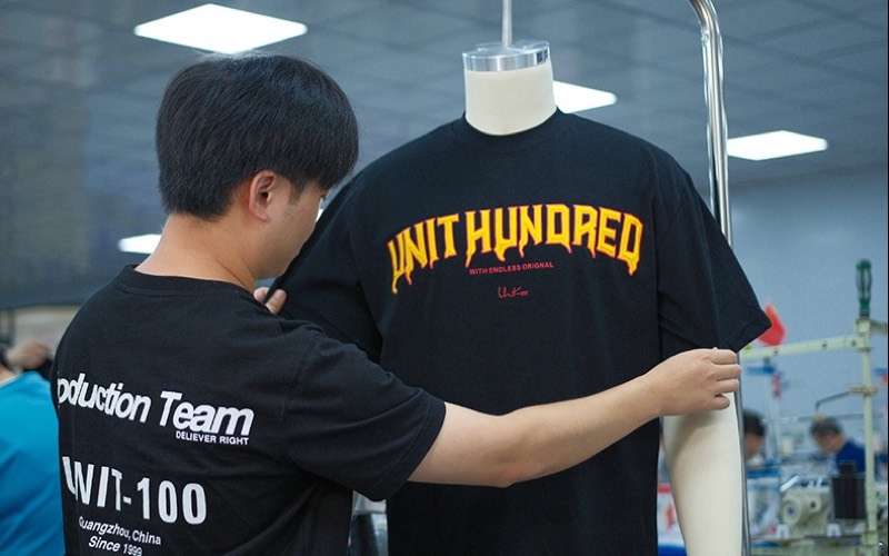 UNIT-100 team member checking a sample T-shirt on a dress form