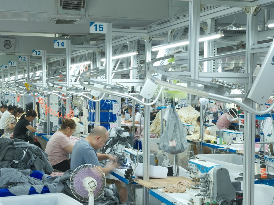 Sewing line at the UNIT-100 factory in Guangzhou, with machinists at numbered stations